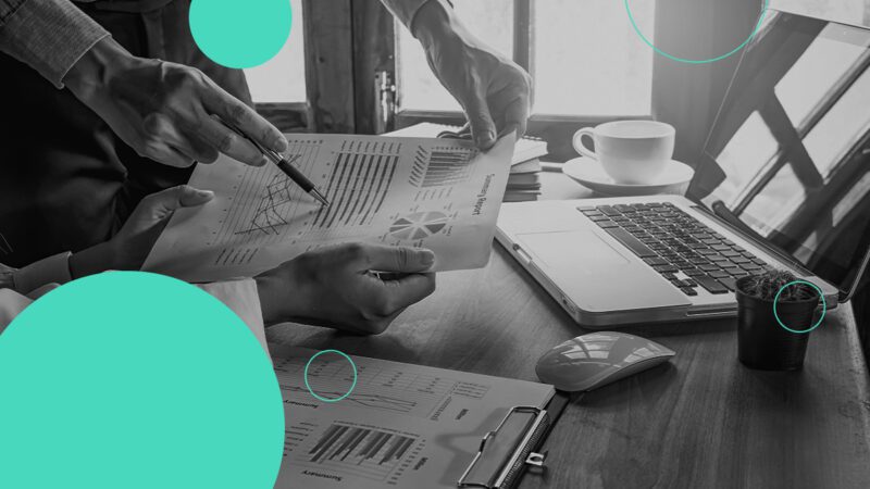 Black and White photo of a person looking at a document at their desk, next to a laptop, for the article 